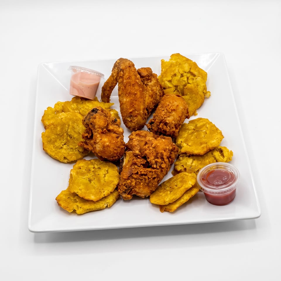 Platter of crispy fried chicken and golden plantains served with pink and red dipping sauces.